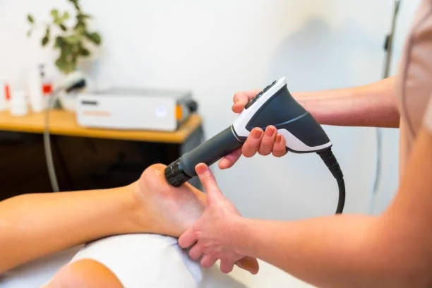A shockwave therapy applicator held against a patient's heel